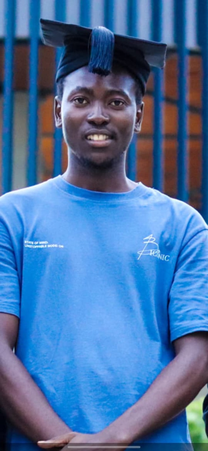 Portrait of Pule.M in a blue shirt and cap.